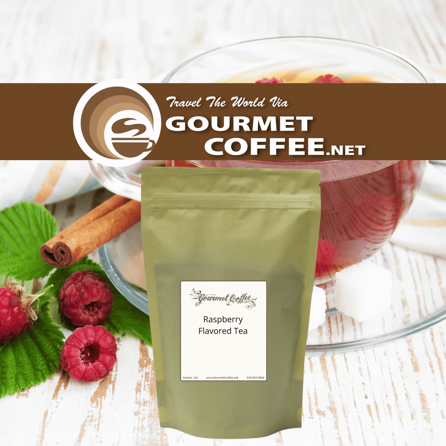 A stand-up pouch of Gourmet Coffee.net Raspberry Flavored Tea placed on a white wood surface with raspberries, cinnamon sticks, green leaves, and a glass of red tea in the background.